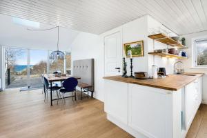 a kitchen with white cabinets and a table with chairs at Unique New Beach-House I Seaview And Space in Vejby