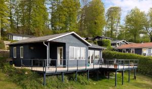 Ein kleines schwarzes Haus mit Veranda und Terrasse in der Unterkunft Neu Restauriertes Sommerhaus Mit Meerblick in Aabenraa