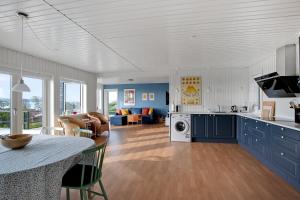 eine Küche und ein Wohnzimmer mit blauen Schränken in der Unterkunft Neu Restauriertes Sommerhaus Mit Meerblick in Aabenraa