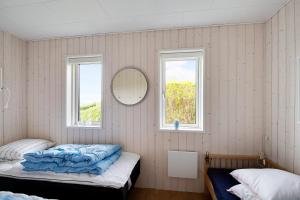 ein Schlafzimmer mit zwei Betten und einem Spiegel und zwei Fenstern in der Unterkunft Neu Restauriertes Sommerhaus Mit Meerblick in Aabenraa