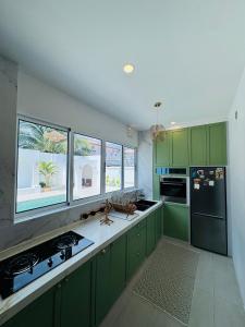 a green kitchen with green cabinets and windows at Bayu senja in Lahad Datu