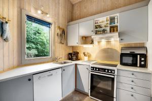 a kitchen with white cabinets and a sink and a window at Family-Friendly Cottage Near The Beach in Gilleleje +14 photos