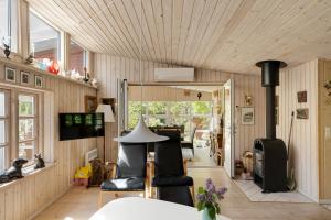a living room with wooden walls and a wooden ceiling at Lovely Cottage In Recreation Area in Åkirkeby