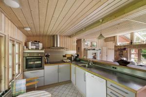 a kitchen with white cabinets and a wooden ceiling at Lovely Cottage In Recreation Area in Åkirkeby +14 photos