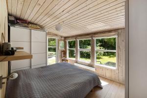 a bedroom of a tiny house with a bed and windows at Lovely Cottage In Recreation Area in Åkirkeby