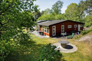 a small cabin with a picnic table in front of it at Lovely Cottage In Recreation Area in Åkirkeby