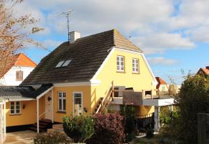 a yellow house with a black roof at Summer House In Årsdale With A Beautiful Sea View in Svaneke