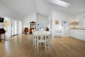 a white dining room with a white table and chairs at New And Cozy House By The Beach And Forest in Hornbæk
