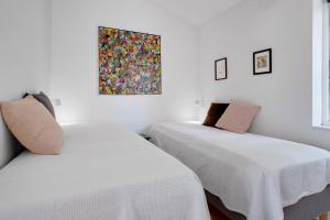 two beds in a room with a painting on the wall at New And Cozy House By The Beach And Forest in Hornbæk