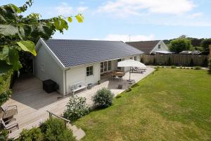 a house with a deck with a table and an umbrella at New And Cozy House By The Beach And Forest in Hornbæk