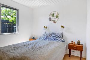 a white bedroom with a bed and a window at Lovely Cottage Full Of Holiday Atmosphere in Rødby