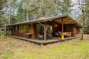 a wooden cabin in the woods with a table and chairs at Nice Summer House In The Middle Of The Forest in Store Fuglede