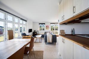 eine Küche und ein Wohnzimmer mit Sofa und Tisch in der Unterkunft Gemütliches Ferienhaus Im Sommerdorf Kerteminde in Kerteminde