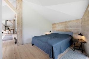 ein Schlafzimmer mit einem blauen Bett und einer Holzwand in der Unterkunft Malerisches Sommerhaus In Der Nähe Ruhiger, Plätschernder Wellen in Kirke-Hyllinge
