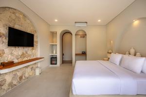 a bedroom with a large white bed and a stone wall at DESAULU VILLAS - Boutique Private Room Pool View in Uluwatu