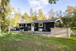 a small black house with a wooden deck at Scenic Summer House On Langeland in Humble
