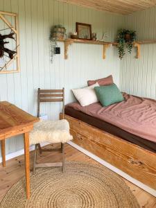 a bed in a room with a table and a table sidx sidx at Shepherd's Hut With Lake View In Ollerup in Vester-Skerninge