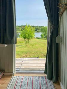 an open door with a view of a field at Shepherd's Hut With Lake View In Ollerup in Vester-Skerninge