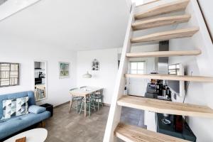 a spiral staircase in a living room with a blue couch at Bornholm Holiday Apartment With Sea View in Allinge