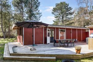a deck with a table and an umbrella at Family-Friendly Cottage Close To The Water in Nykøbing Sjælland