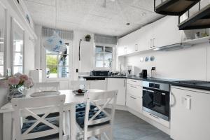 a kitchen with white cabinets and a table with chairs at Holiday In The First Row To The Water in Dannemare