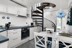 a kitchen with white cabinets and a spiral staircase at Holiday In The First Row To The Water in Dannemare
