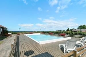 a swimming pool on a wooden deck with chairs around it at Bright And Cozy Summer House With Sea View in Hasle