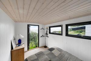 a bedroom with a bed and two windows at Architect Designed Holiday Home With Sea View in Gudhjem