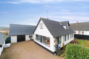 a white house with a black roof at Modern House With Space For Relaxation in Åkirkeby