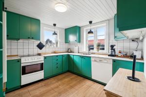 a green kitchen with white appliances and green cabinets at Modern House With Space For Relaxation in Åkirkeby