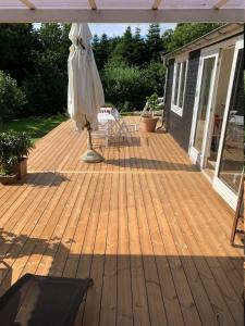 a wooden deck with an umbrella and a chair on it at Cozy And Modernized Fishing Cabin in Hornslet +5 photos