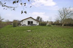 ein weißes Haus auf einem Feld mit einem grasbewachsenen Hof in der Unterkunft Schönes Neu Renoviertes Sommerhaus Am Meer in Frørup