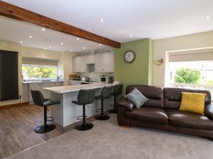 a living room with a leather couch and a kitchen at Dalar Deg in Rhiw +24 photos