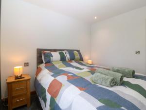 a bedroom with a bed and a night stand with a lamp at Dalar Deg in Rhiw