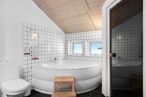 a white bathroom with a tub and a toilet at Summer House In Beautiful Nature In Brunshuse in Hårby +16 photos