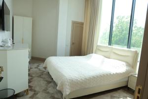 a white bedroom with a bed and a window at Horev Medical Center in Tashkent