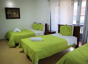 a hotel room with two beds with green sheets at Hotel Bera-k in Villa de Leyva +11 photos