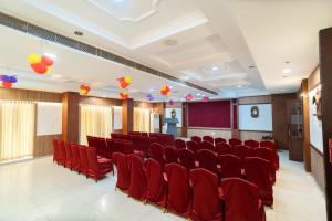 a conference room with red chairs and a stage at PLA Residency Tanjore in Thanjāvūr