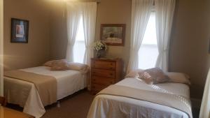 a bedroom with two beds and a dresser and window at Carraway Guest House in Canal Winchester