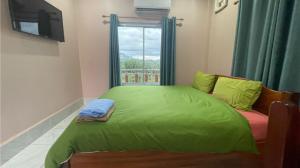 a bedroom with a green bed and a window at khounxub view hotel in Ban Pho Touane