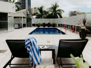 a pool on a building with two chairs and a table at Mercure Brisbane Spring Hill in Brisbane