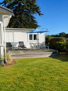 a patio with chairs and a table with a blue umbrella at Farm Stay | Near Airport & Mystery Creek in Tamahere