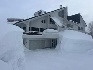 a house with a pile of snow in front of it at Momo Lodge Madarao in Iiyama