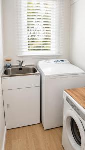 a white kitchen with a sink and a washing machine at Farm Stay | Near Airport & Mystery Creek in Tamahere