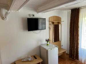 a room with a refrigerator and a tv on the wall at Paradis in Buşteni