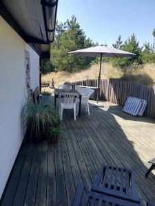 a wooden deck with two chairs and an umbrella at Holiday Home On A Huge Nature Plot in Skagen +19 photos