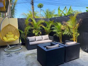 a patio with a couch and chairs and palm trees at Yellow Monkey Hostel Uluwatu in Uluwatu