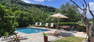 a pool with a table and chairs and an umbrella at Donatos Parga - Apartments & Studios in Parga