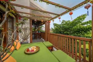 a green table on a balcony with a bowl of fruit at Hoi An Chic - Green Retreat in Hoi An +45 photos