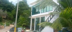 a white house with glass windows and a palm tree at water fall resort soksan in Phumĭ Kaôh Rŏng